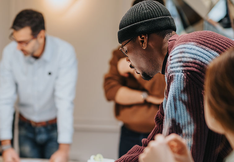 Business team actively engaged in a workshop, collaborating over documents and using laptops in a well-lit modern office environment.