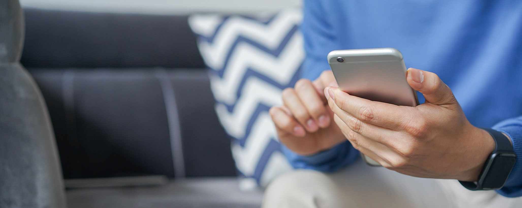 close up man hand hold mobile cell phone device and sitting on sofa in living room to communication video call with other for new normal lifestyle