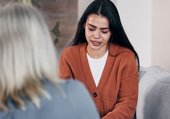 Sad woman, therapist and crying in consultation for addiction, mental health or support counseling.